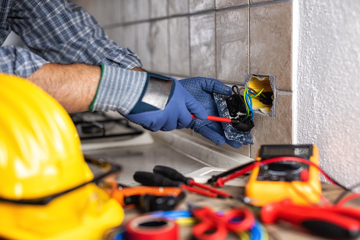 Electrician at work with safety equipment on a residential elect Electrician at work with screwdriver fixes the cable in the sockets of a residential electrical system.